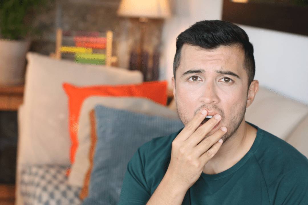 young man covering mouth shocked look
